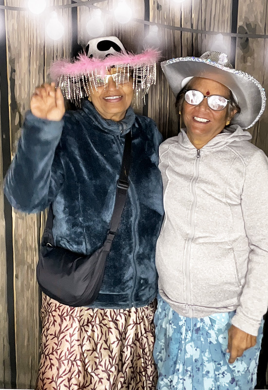 Two happy grandmothers smiling and posing with fun hats at a photo booth party in Torrance, California