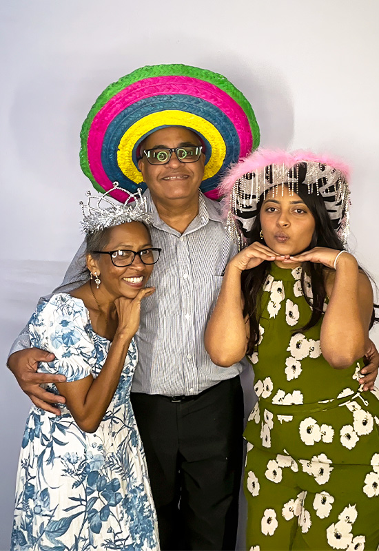 Family of three wearing silly hats and posing in a photo booth at an event in Wilmington, California
