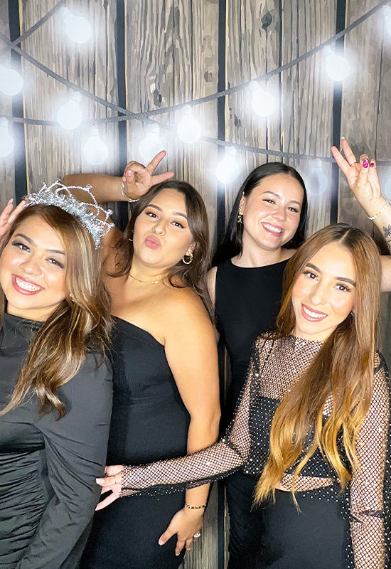 Four young women smiling and posing at a Quinceañera photo booth in Lawndale, California