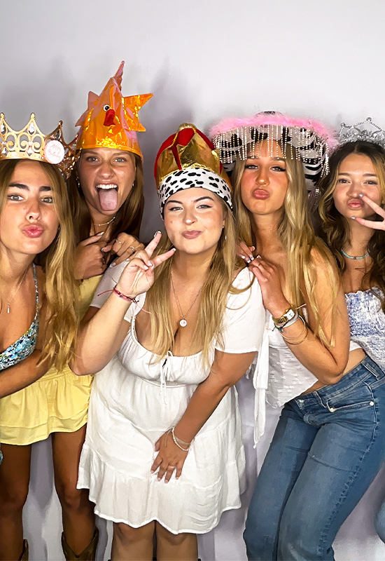 Five girls smiling and making silly faces with photo booth props at a Sweet Sixteen party in Fullerton, California