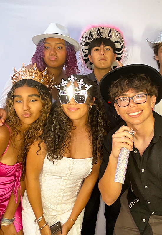 Group of teens smiling and posing with photo booth props at a birthday party in Palos Verdes, California