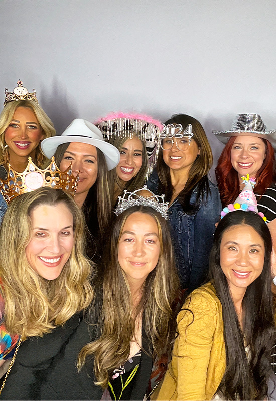 Group of women smiling and making silly faces with photo booth props at a birthday party in Carson, California