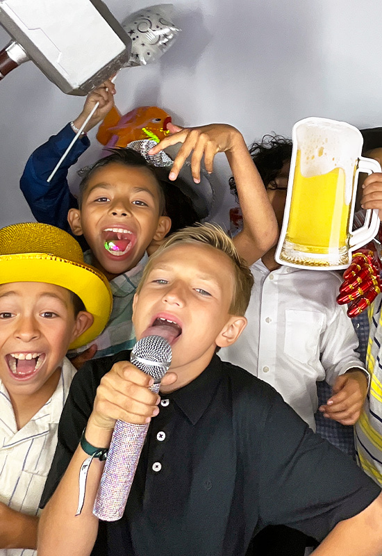 Group of kids smiling and making silly faces with photo booth props at a school event in Gardena, California