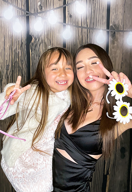 Mother and daughter smiling and making peace signs at a Quinceañera photo booth in Redondo Beach, California