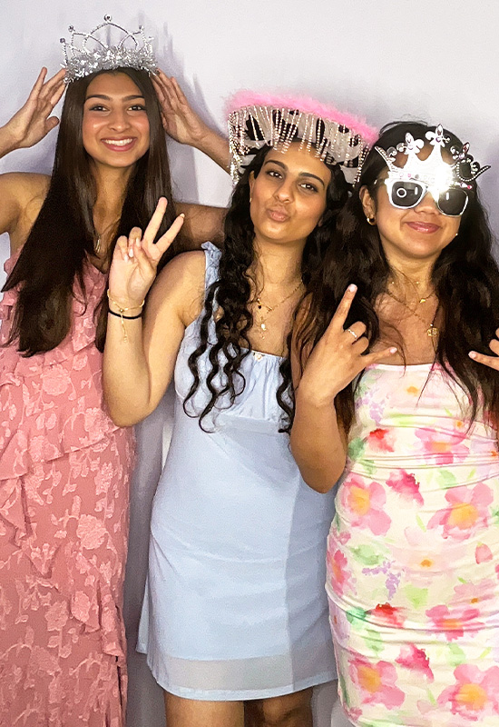 Three girls smiling and posing with silly photo booth props at a wedding party in Torrance, California