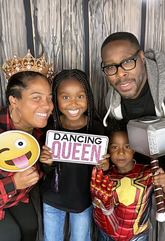 family posing in photo booth with crown emoji sign and toy hammer in Compton California