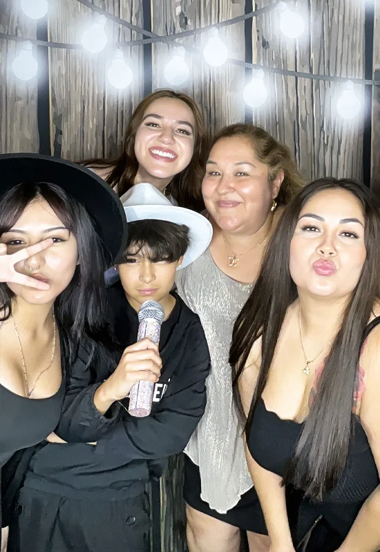 group of people including women and child using photo booth with microphone prop in Carson California