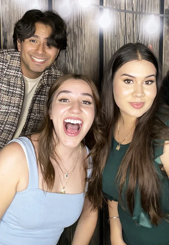 three friends smiling at photo booth at house party in Hawthorne California