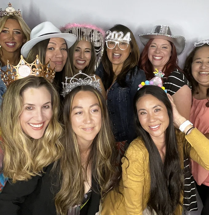 group of moms using photo booth wearing props and hats at party