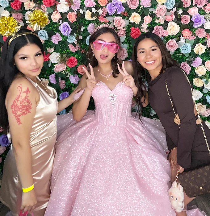 quinceanera making peace sign with friend holding BFF sign at photo booth in Carson California